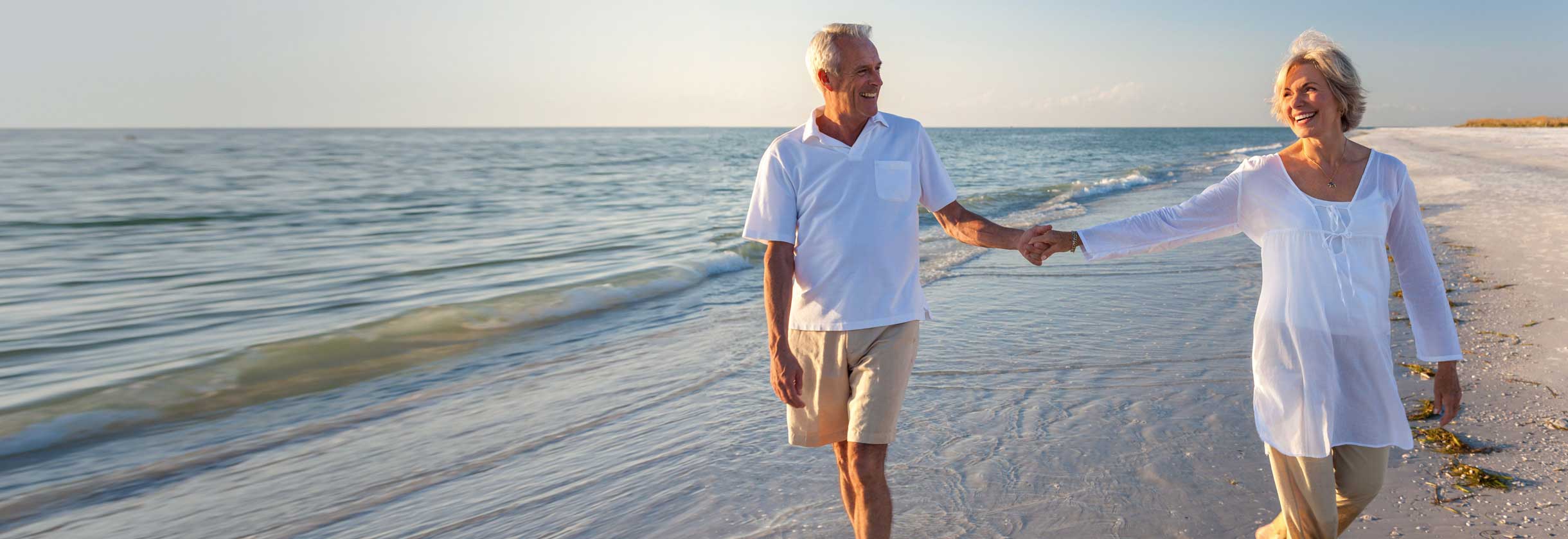 Senior couple holding hands while walking on the beach